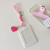 A pink PU credit card and ID holder keychain with a heart charm and a matching pink lanyard resting on a white background.