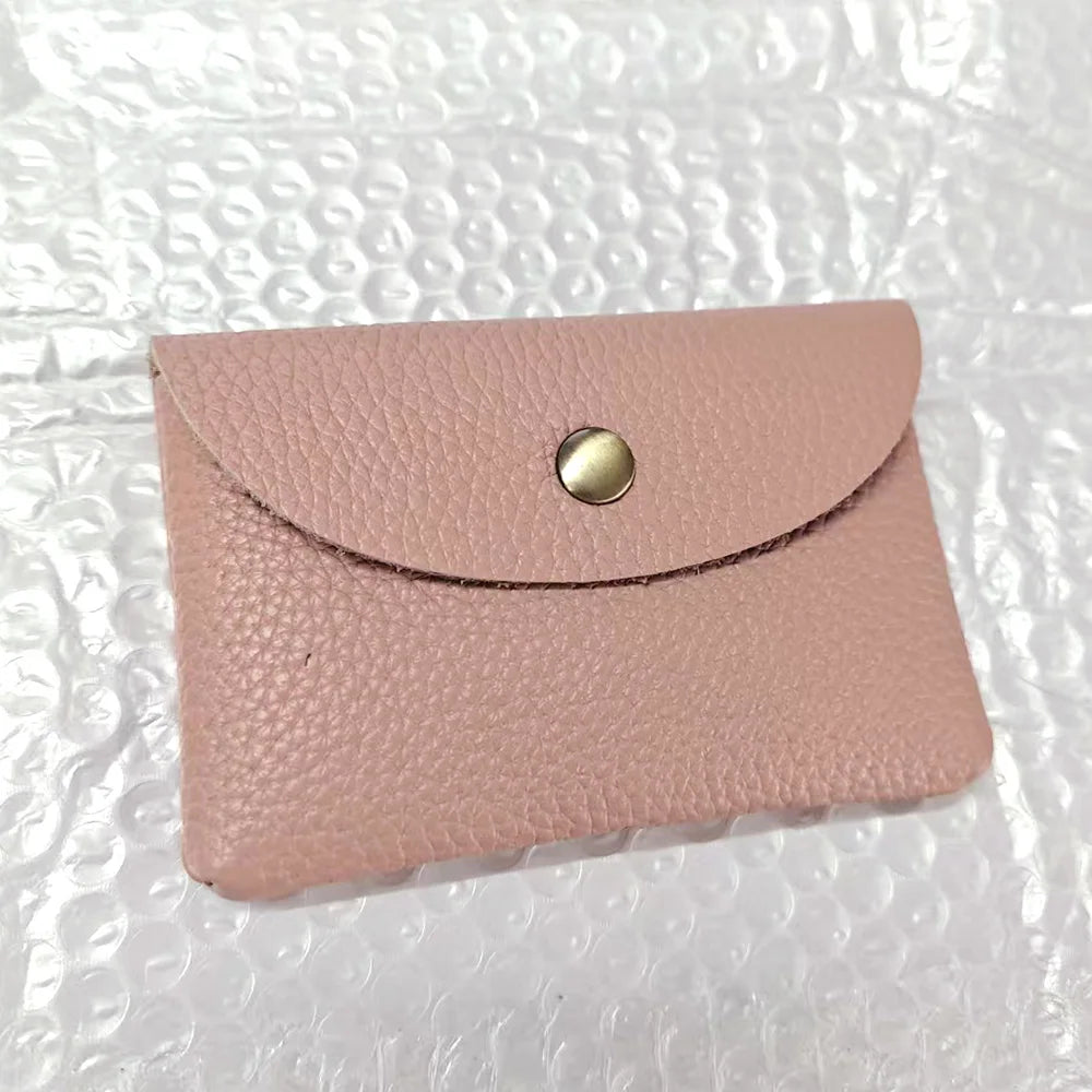A pale pink genuine leather card holder with a gold-toned stud closure.