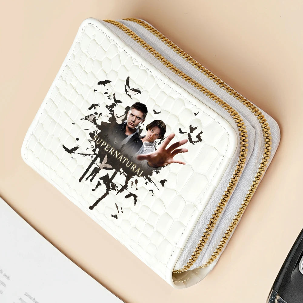 A white quilted wallet with gold stitching and a black supernatural graphic is shown on a light background.