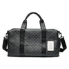 A black leather duffle bag with padded straps and a patterned fabric exterior is shown against a white background.