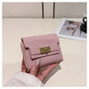 A hand holds a pink multi-slot card holder with a gold accent against a white background.