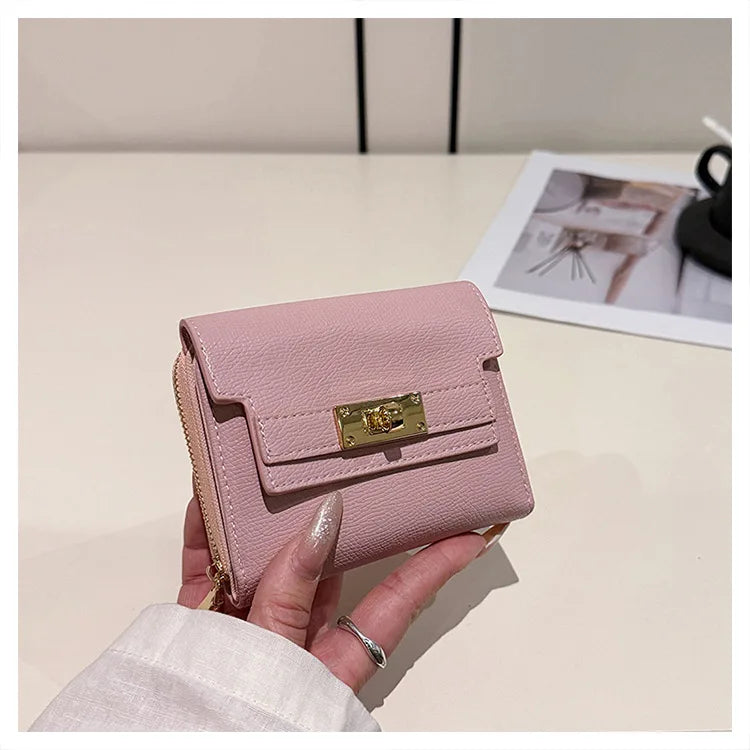 A hand holds a pink multi-slot card holder with a gold accent against a white background.