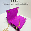 A vibrant purple velvet clutch bag with gold embroidery and a gold chain strap.