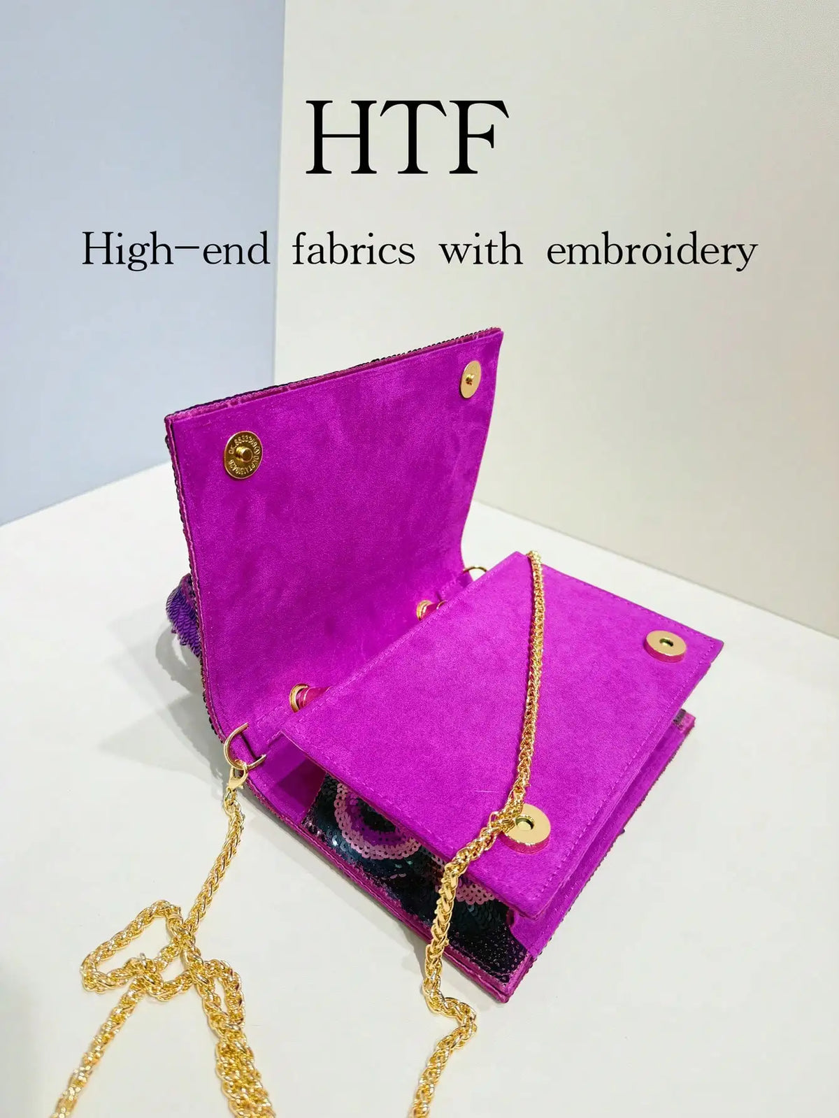 A vibrant purple velvet clutch bag with gold embroidery and a gold chain strap.