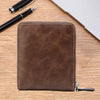 A brown men's PU waxed oil leather bifold wallet resting on a wooden surface next to a pen.