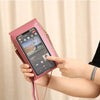 A hand holds a pink women's touch screen crossbody shoulder bag with a smartphone displaying an interface.