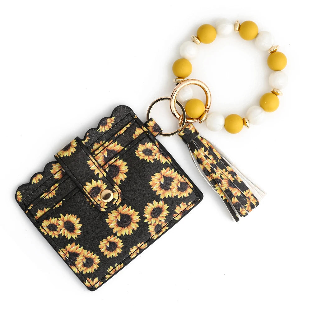 A silicone bead and leather card wallet featuring a black and yellow sunflower pattern and white and yellow beads.