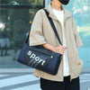 A person wearing a beige jacket is holding a navy blue and gray sports backpack.