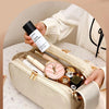 A hand holds a beige PU leather travel makeup organizer with double zippers, showing various cosmetic bottles inside.