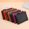A collection of genuine leather mini zipper coin and card purses in various colors lined up on a light background.