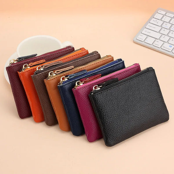 A collection of genuine leather mini zipper coin and card purses in various colors lined up on a light background.