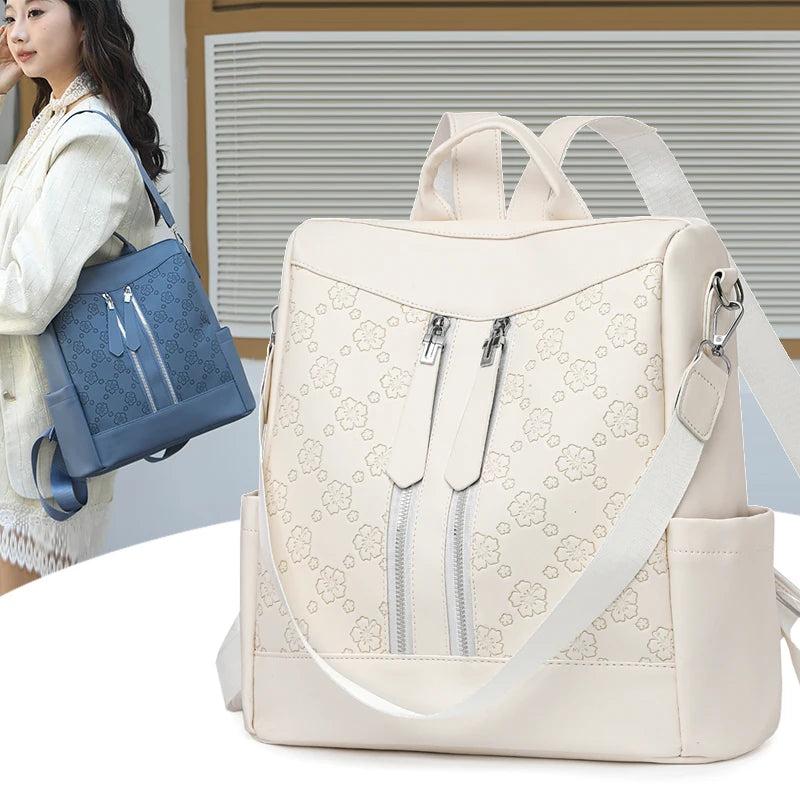 A beige leather anti-theft women's backpack with light floral pattern and silver zippers.
