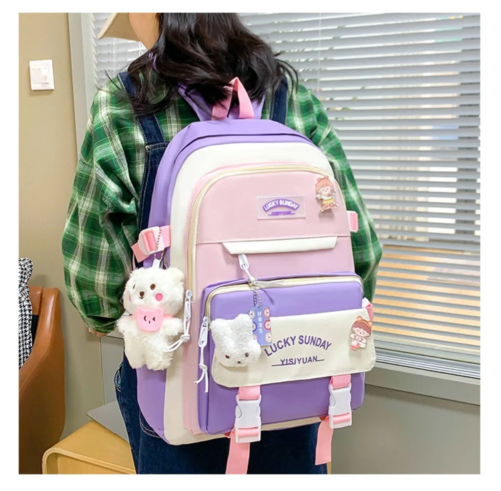 A pink and purple nylon backpack set featuring cartoon designs carried by a person.