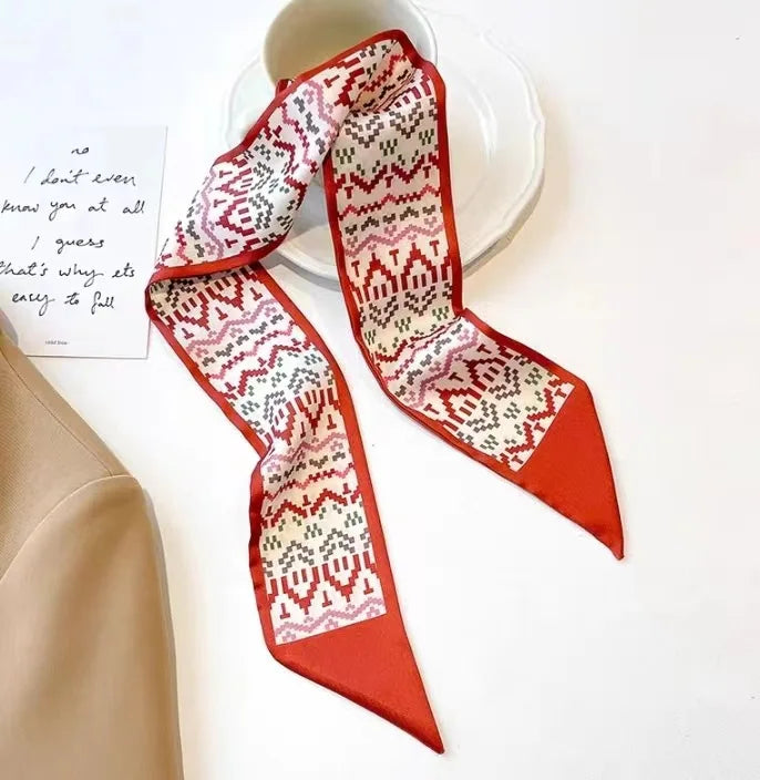 Foulard pour cheveux floral en soie plié avec motifs géométriques rouges et blancs à côté d'une note manuscrite.