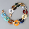 A multi-color acrylic chain strap featuring various shades of green, brown, white, silver, and blue.