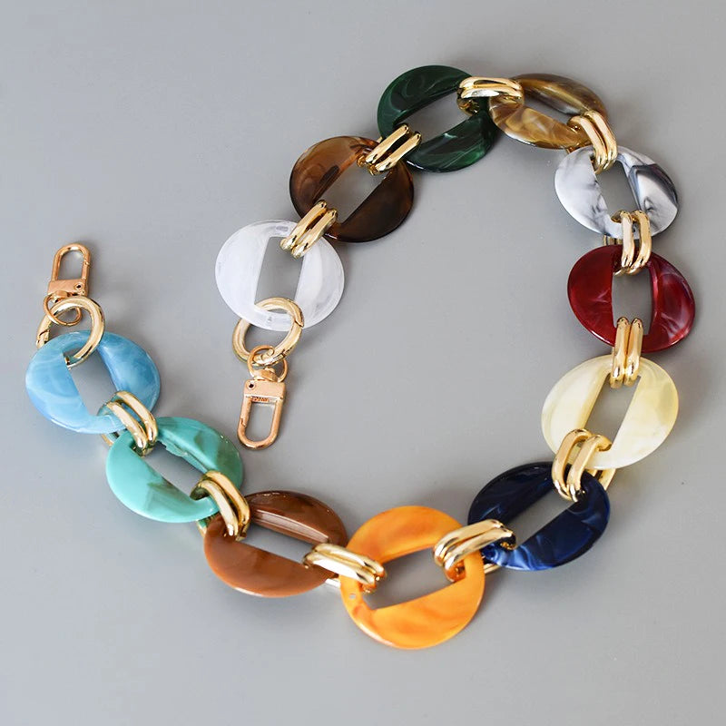 A multi-color acrylic chain strap featuring various shades of green, brown, white, silver, and blue.