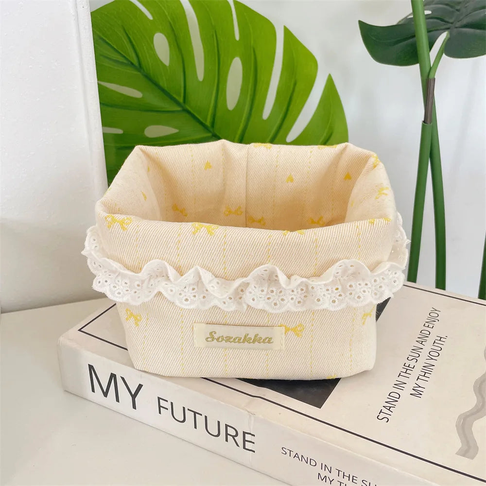 Light pink fabric storage basket with a scalloped edge and yellow heart details resting on a wooden box.