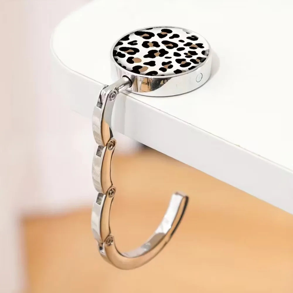 Silver round metal bag hanger with a leopard print top and a curved silver chain.