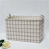 A rectangular beige fabric storage basket with a black grid pattern and handles, shown against a white background.