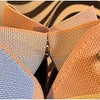 Close-up of a geometric colorblock knitted bucket bag featuring shades of peach, beige, and blue.
