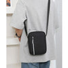 A black durable waterproof crossbody bag with a black strap is shown against a light gray t-shirt.