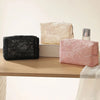 Three cosmetic and jewelry organizer bags in black, cream, and pink lace mesh displayed on a wooden surface.