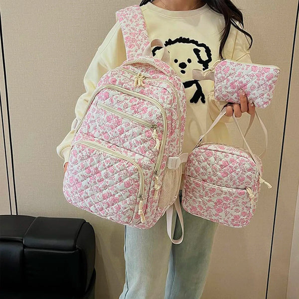 A young woman is holding a pink floral quilted backpack set with a yellow sweatshirt.