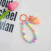 A colorful bead necklace featuring pink, yellow, and blue beads with a pink bow charm attached to an orange O-ring clip.