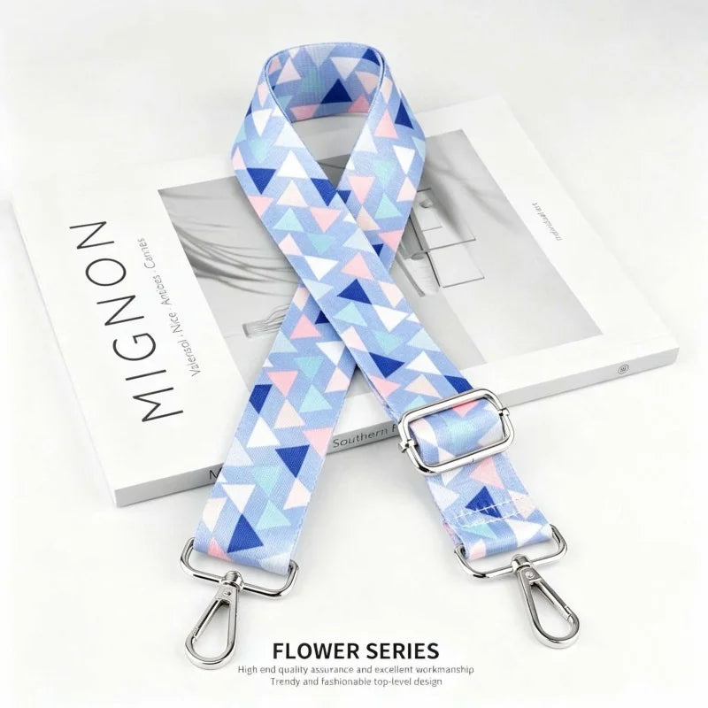 A light blue and pink patterned nylon shoulder strap for bags and purses displayed next to a white box.