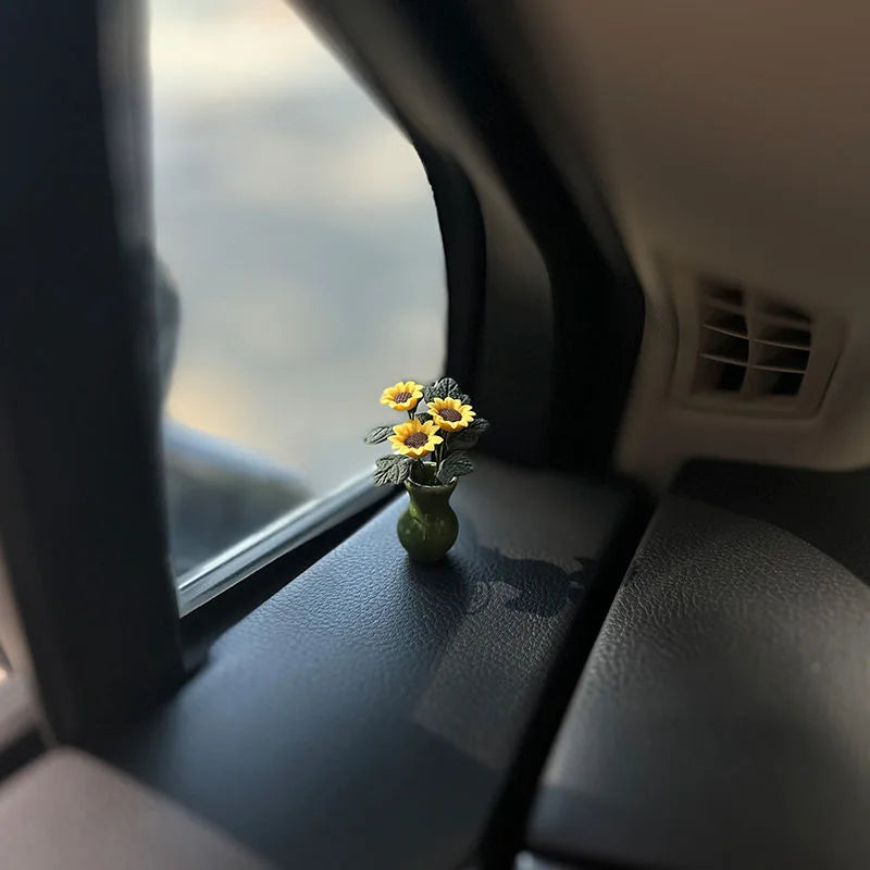 Eine kleine gelbe Rose in einer grünen Vase auf der Innenseite einer Auto-Verkleidung, sichtbar durch das Fenster.