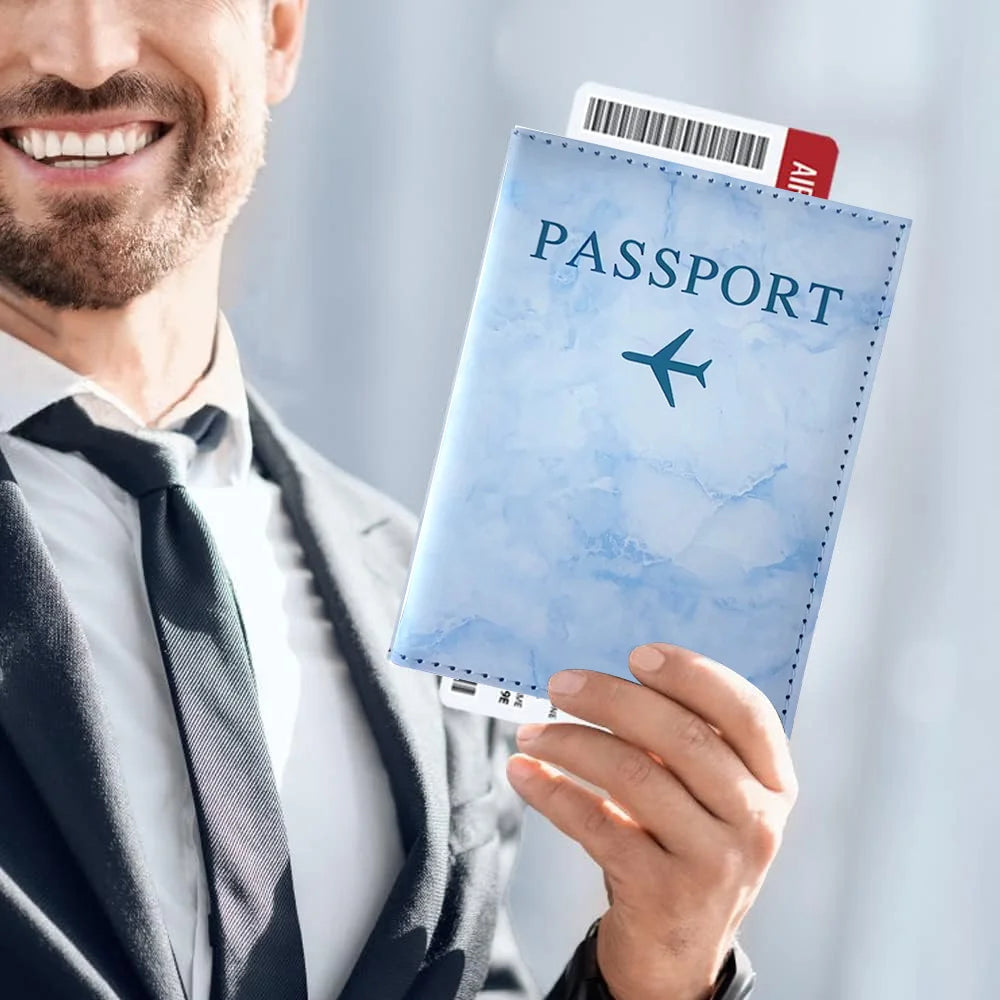 A man holds a blue passport card holder with a plane design and an identification card.