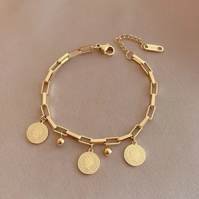 A gold stainless steel charm bracelet featuring a portrait pendant and various charms.