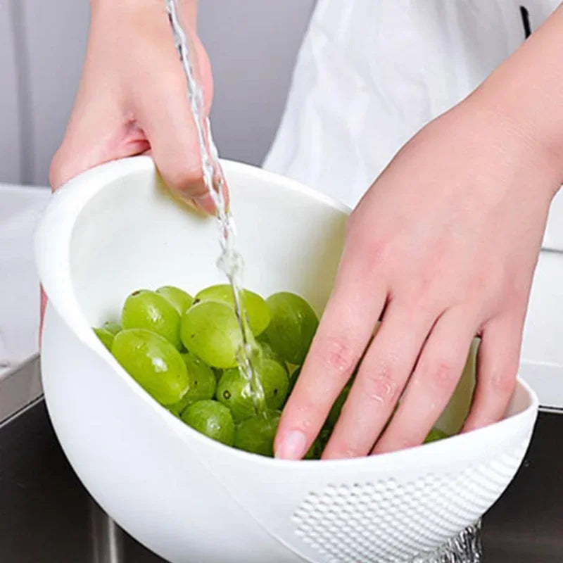 Hands are pouring green grapes into a white plastic drain and storage basket.