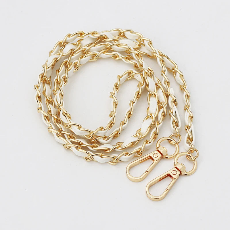 A stack of gold and white leather chain straps for an adjustable crossbody purse.