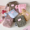 A collection of leopard print and pink fuzzy makeup bags for skincare organization.