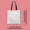 A white canvas tote bag with black handles, shown vertically against a pink background.