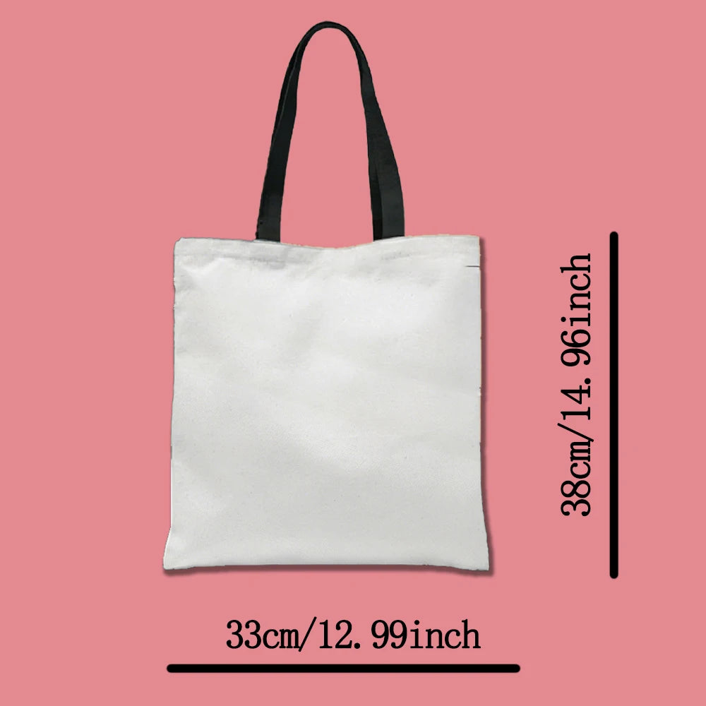 A white canvas tote bag with black handles, shown vertically against a pink background.