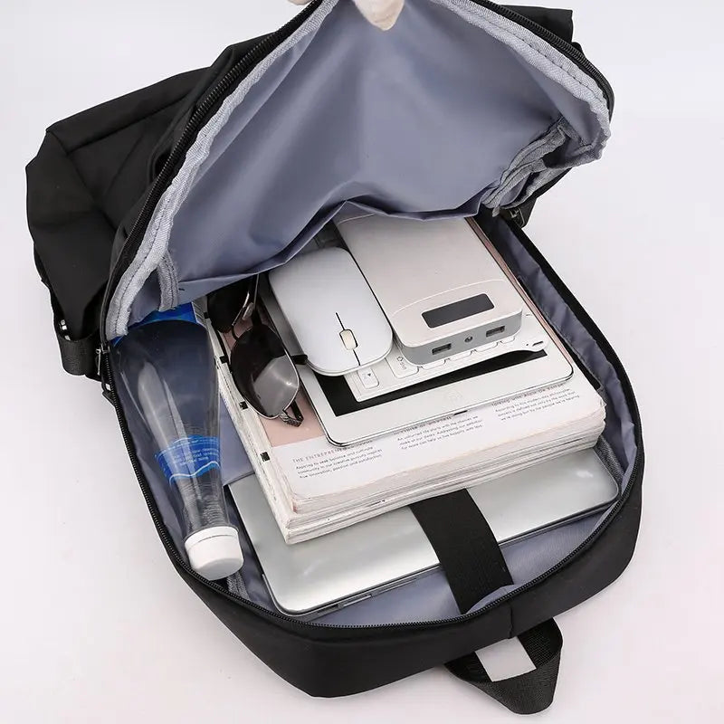 Offener schwarzer Rucksack mit weißem Laptop, Maus und anderen Elektronikzubehörteilen darin.