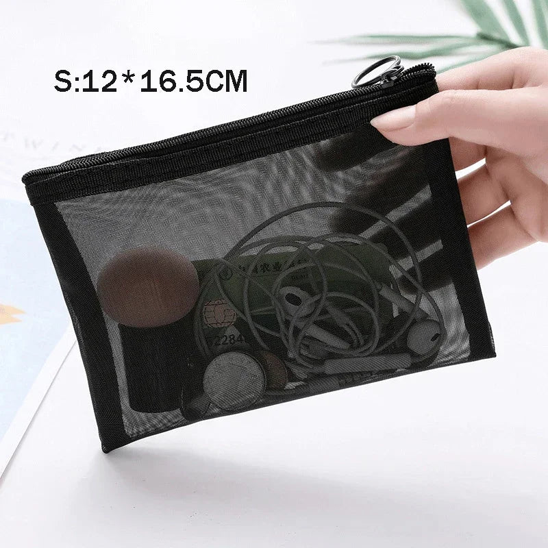 A hand holds a black mesh cosmetic storage pouch with a zipper, showing the clear netting and contents.