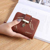 Cartera clutch de cuero PU marrón con herrajes dorados sobre un documento de papel blanco.