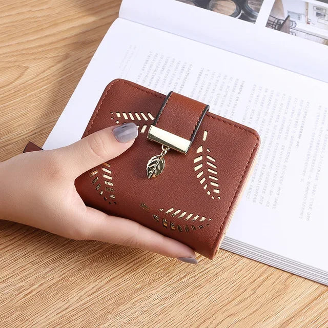 Cartera clutch de cuero PU marrón con herrajes dorados sobre un documento de papel blanco.