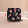 Black pouch with pink floral pattern designed for compact sanitary pad storage or tampon holding.