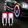 A pair of bright LED tire valve stem lights illuminating a dark car wheel.