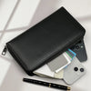 A black multi-card commuter wallet is shown open, displaying various cards and a black pen on a white surface.