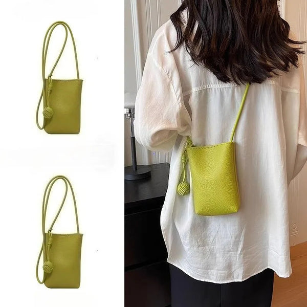 A woman is holding a lime green leather crossbody bag against a white shirt.