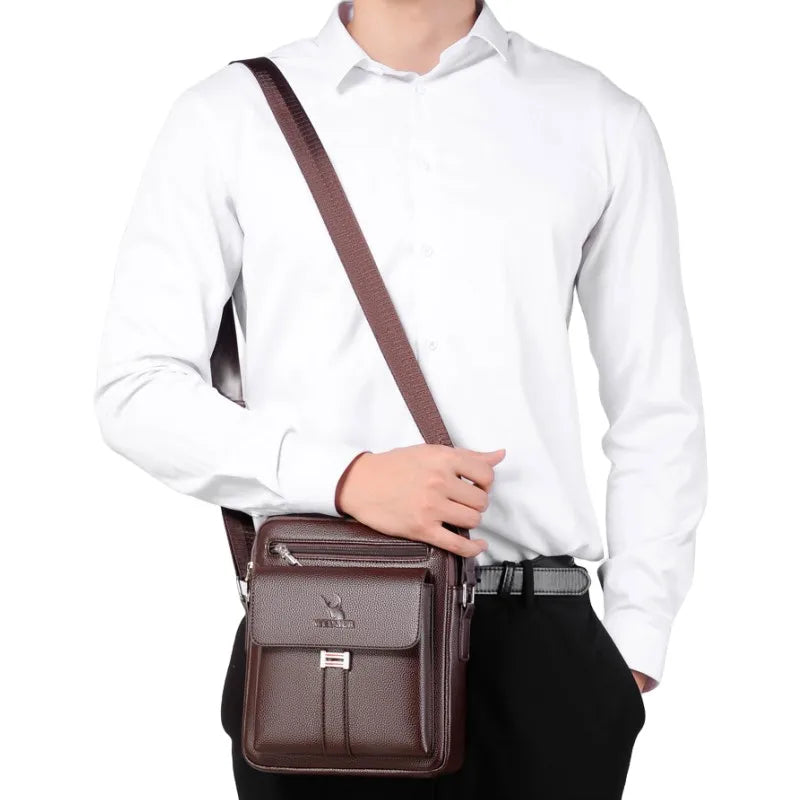 A brown vintage PU leather crossbody messenger bag worn by a man in a white shirt and black pants.
