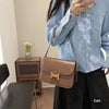 Eine Frau in blauem Shirt und schwarzen Hosen hält eine braune Ledertasche über eine Schulter.