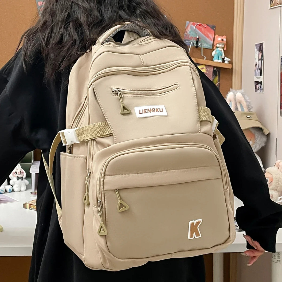 A beige lightweight nylon college backpack is shown from the back, carried by a person.