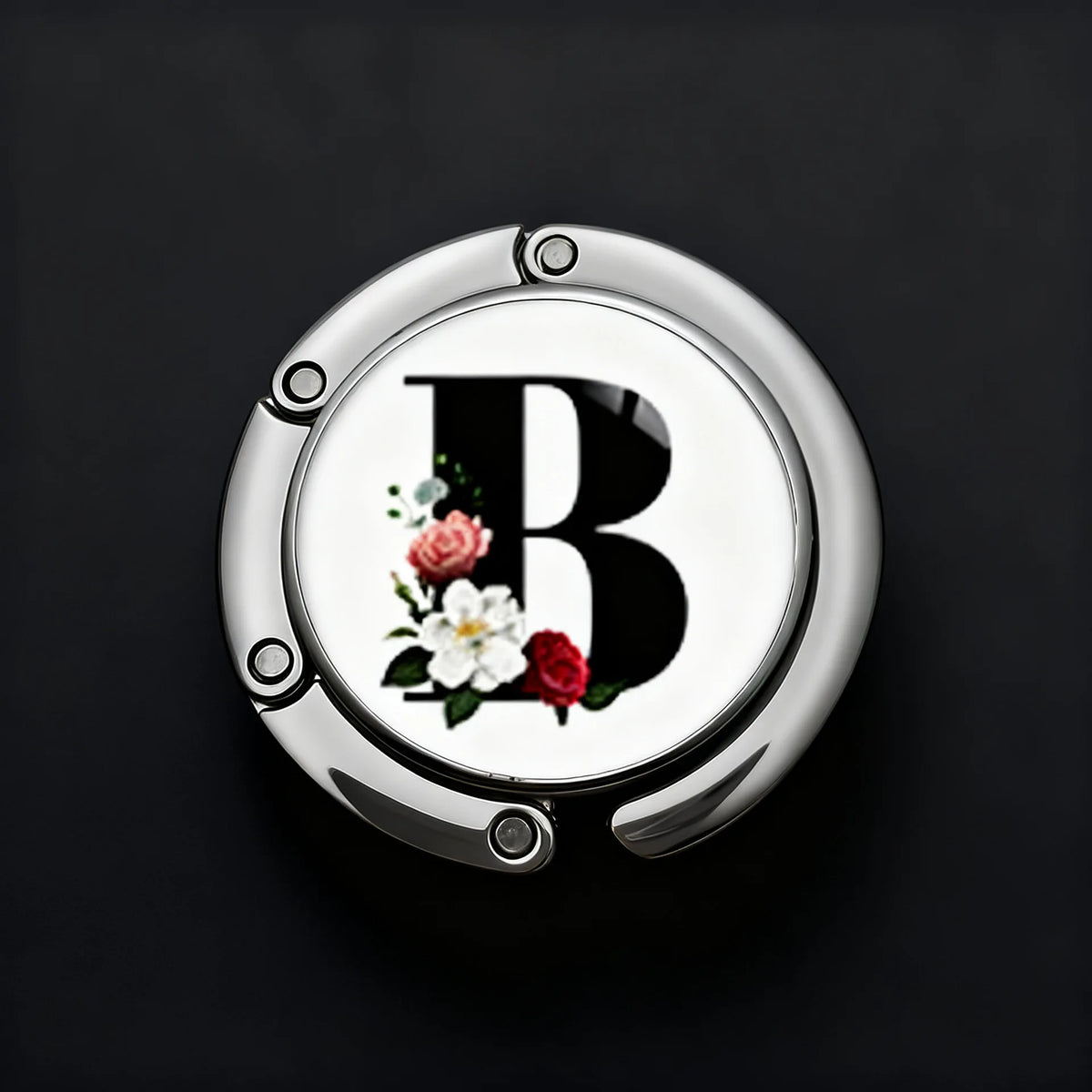 A silver, round letter B with a floral design is shown on a dark background.