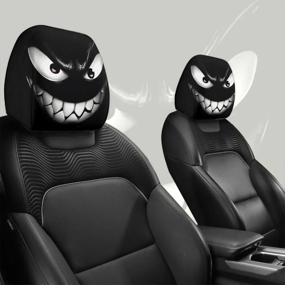 Un paire de housses décoratives pour tête de siège de voiture noires avec des visages de monstres menaçants et souriants.